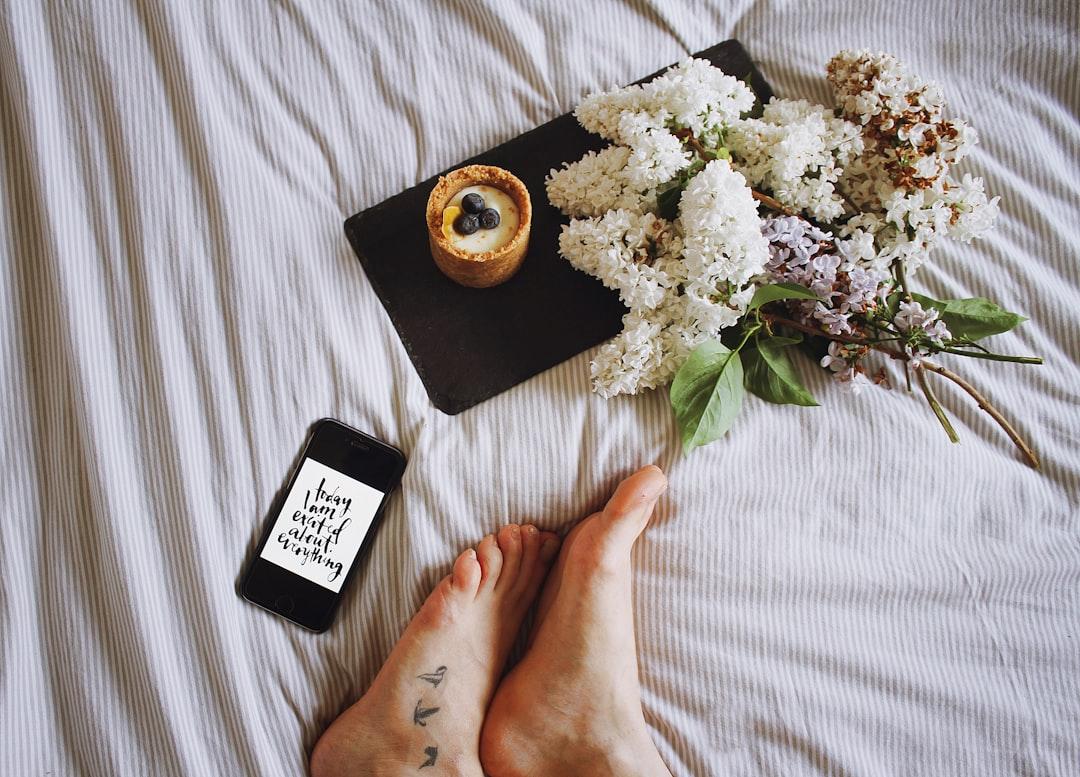Egy lapos fekvő kép egy okostelefonnal, amely egy Instagram-bejegyzést, egy kávéscsészét és egy kis virágot mutat.