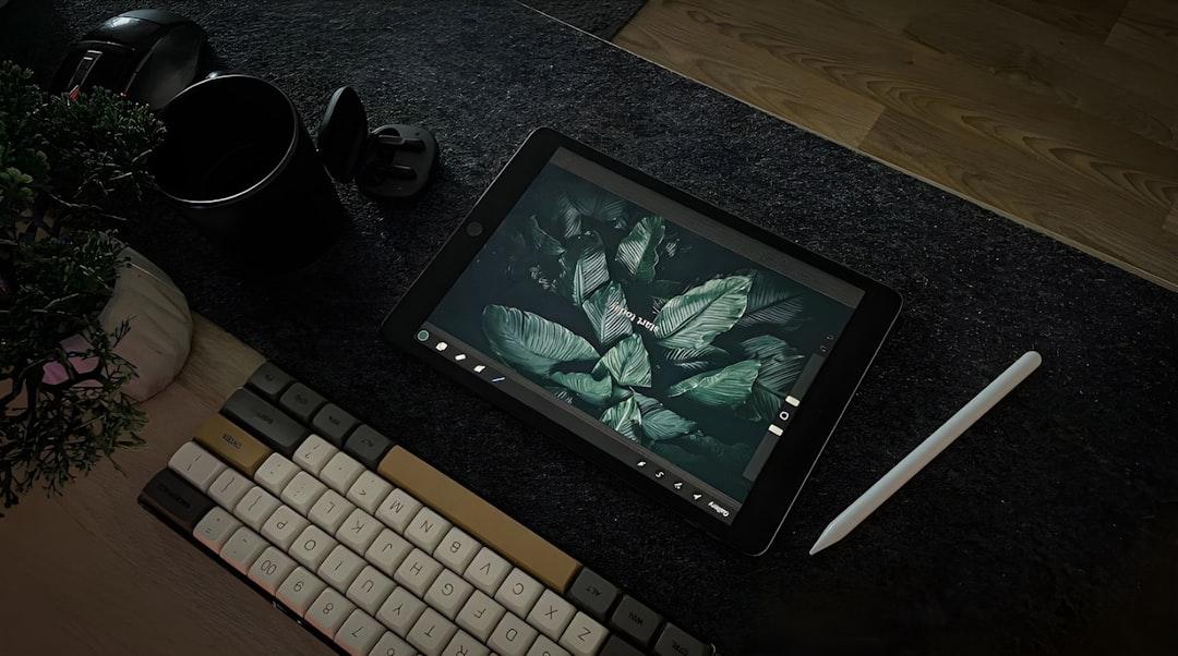 アーティストの机には、ピクセルアートを表示する描画タブレットがあり、コーヒーや植物が近くにあります。