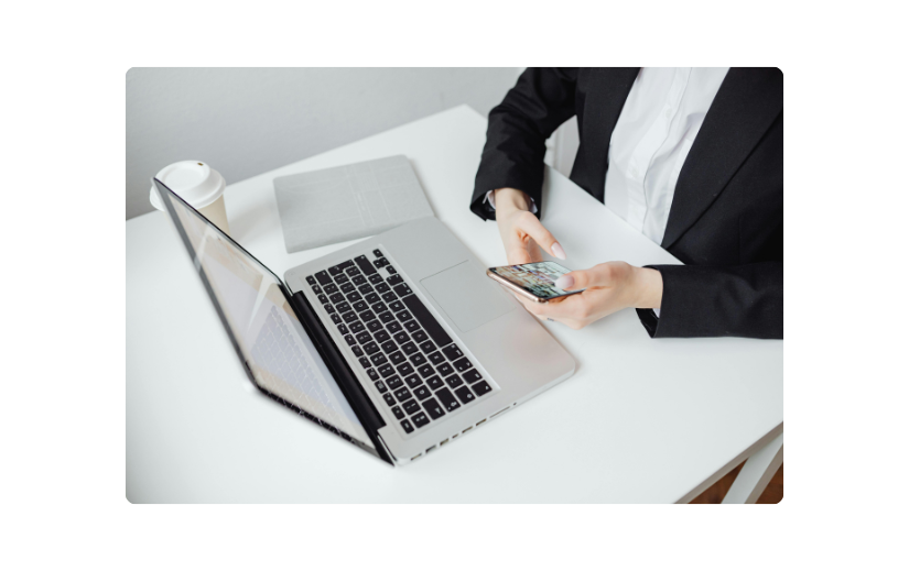Profesional de negocios usando una computadora portátil y un teléfono, ilustrando marketing por SMS y marketing por correo electrónico para el crecimiento del negocio.