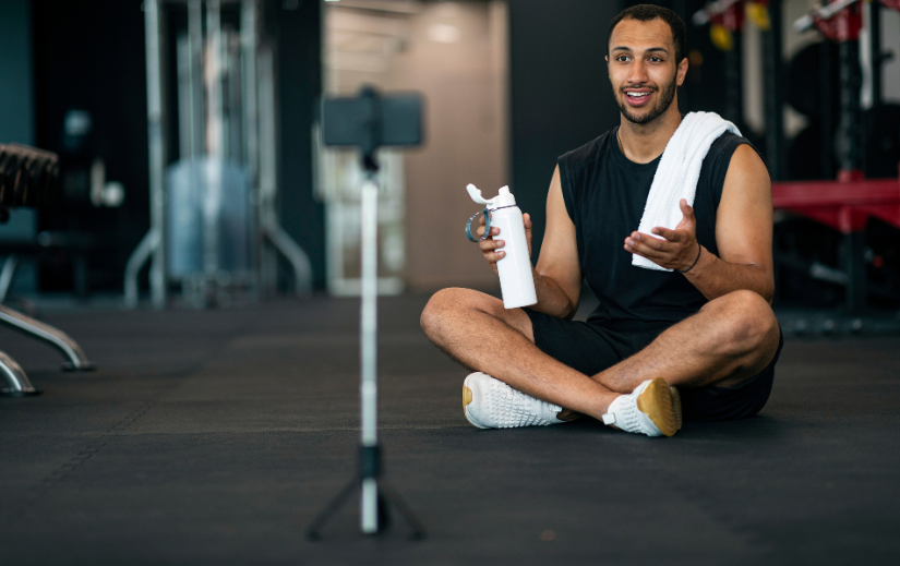 Fitnessinfluencer die een video opneemt in de sportschool over strategieën voor loyaliteitsopbouw voor eCommerce-merken.