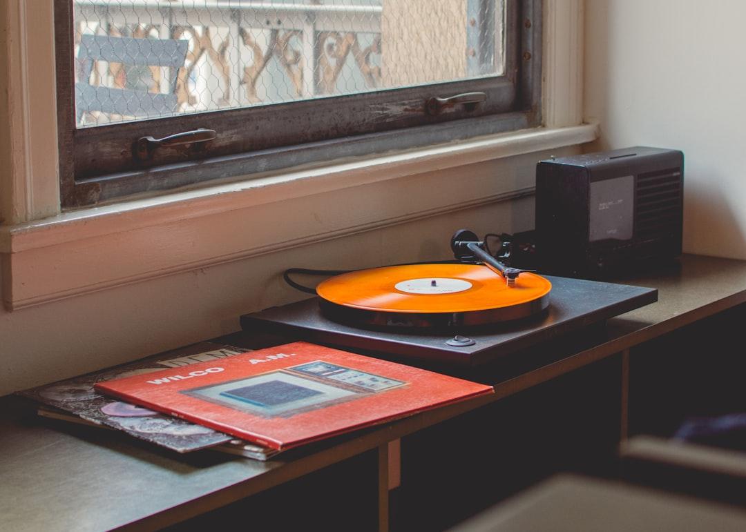 Egy vintage lemezlejátszó közeli felvétele, pörgő bakelitlemezzel. Az albumművészet absztrakt, narancssárga és szőke örvényekkel, Frank Ocean albumesztétikájára emlékeztetve. A világítás meleg és hangulatos.