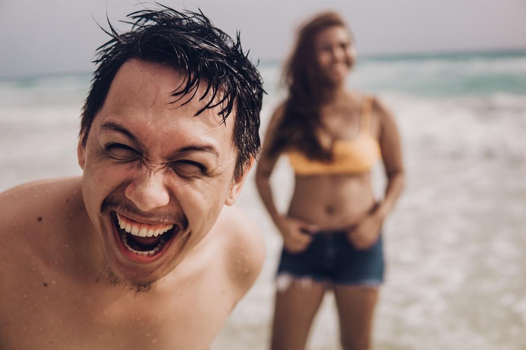 Skupina přátel se směje a dělá si selfie na pláži.