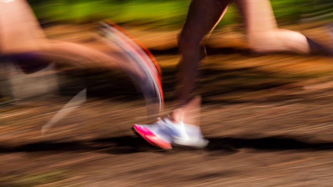 A close-up of a person's running shoes on a track